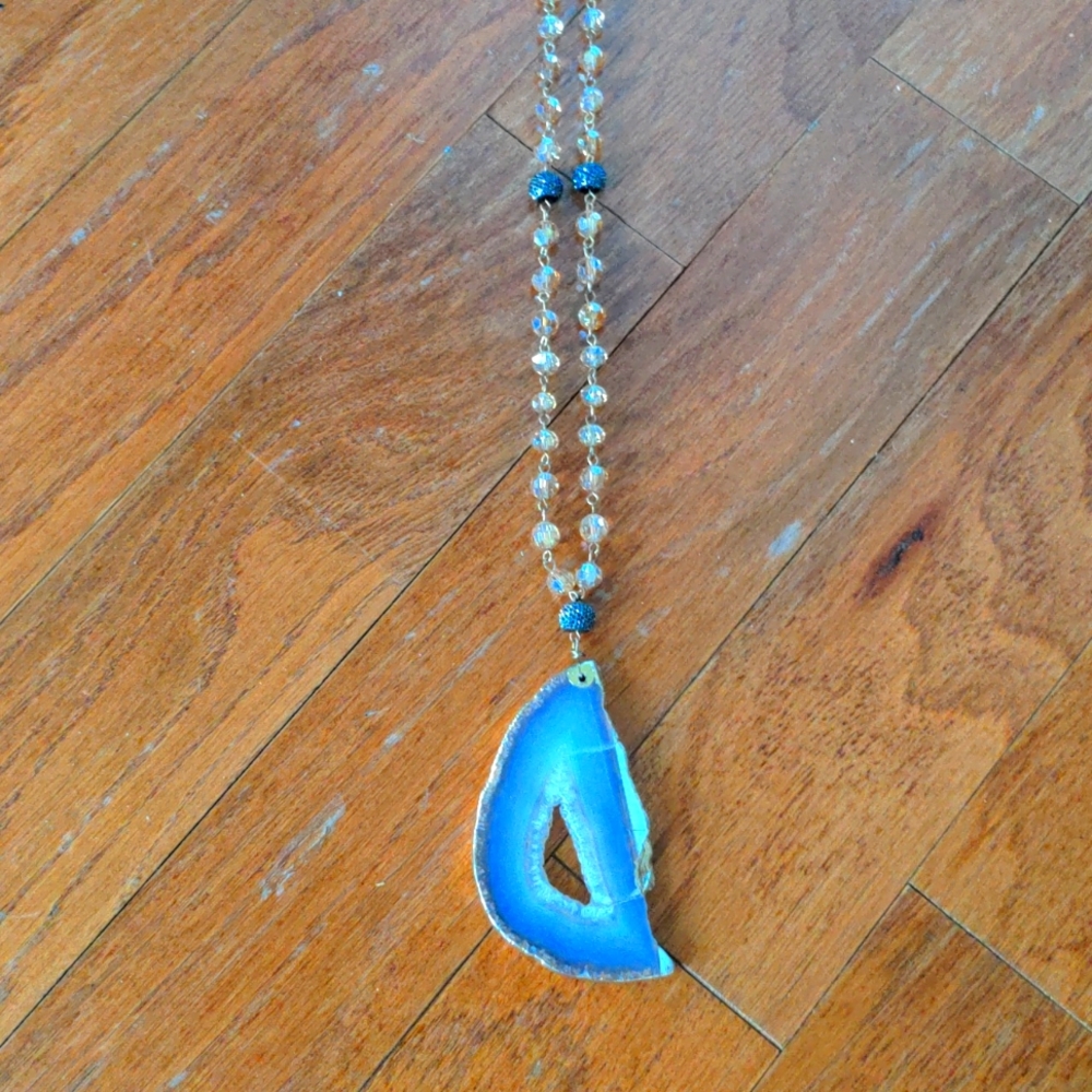Rose gold necklace, with a large light purple gemstone on the end.